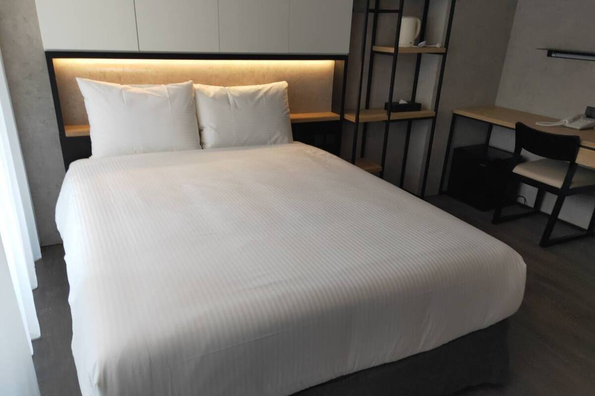 Una habitación de hotel moderna con una cama grande, un escritorio y una silla.