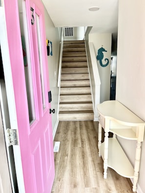 Un escalier avec des marches en bois et une porte rose sur la gauche.