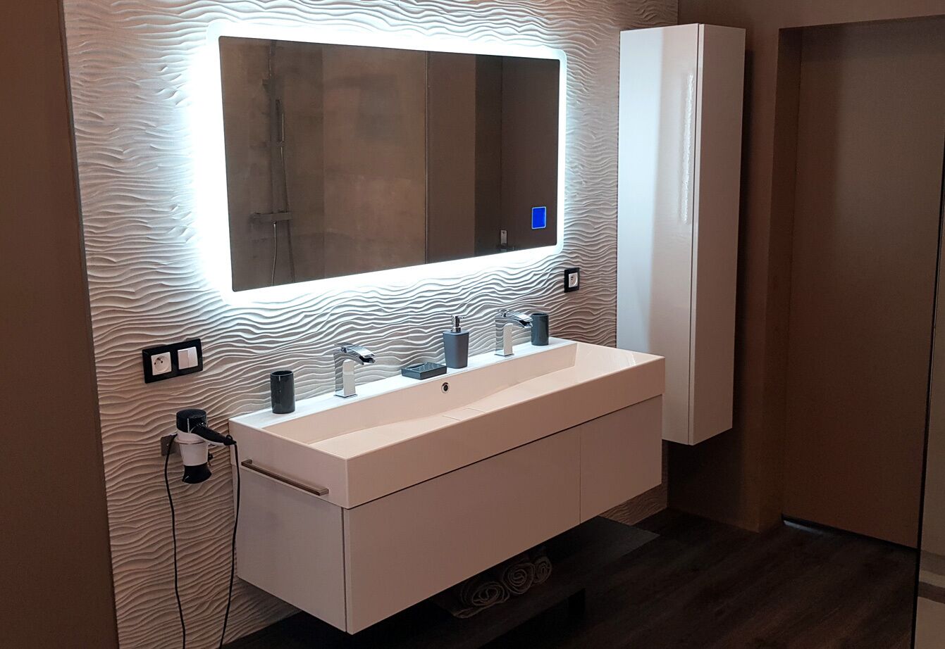 Une salle de bain moderne avec un grand miroir, un meuble-lavabo blanc et un placard intégré.