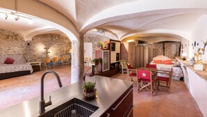 A spacious room with a kitchen area, a dining table, and a bed. - calamarta_ cultural tourism (Santa Coloma de Queralt)