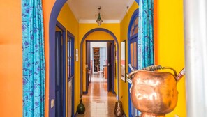 A hallway with vibrant yellow and blue walls, an arched ceiling, and a large copper pot on the right. - calamarta_ cultural tourism (Santa Coloma de Queralt)