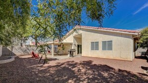 A single-story house with a covered patio, a barbecue grill, and a small outdoor seating area. - Beautiful Las Vegas home (North Las Vegas)