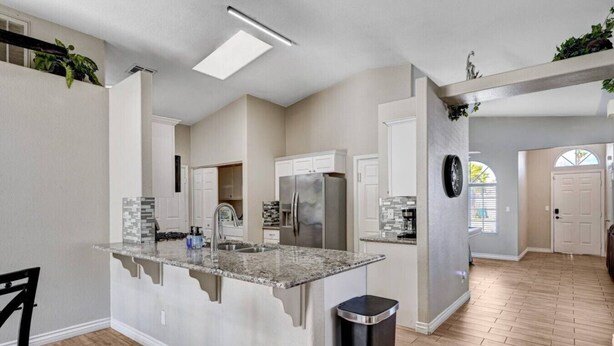 A modern kitchen with a central island, built-in appliances, and a trash can. - Beautiful Las Vegas home (North Las Vegas)
