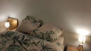 Ein Bett mit einer blumigen Tagesdecke, zwei Nachttischlampen und einem an der Wand befestigten Spiegel.