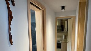 A narrow hallway with wooden flooring and a door leading to a kitchen area. - Ferienwohnung Fuchsbau Vitte (Insel Hiddensee)