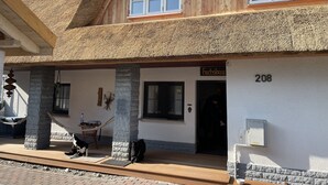 A building with a thatched roof, a stone pillar, and a sign reading "Fuchsbou". - Ferienwohnung Fuchsbau Vitte (Insel Hiddensee)