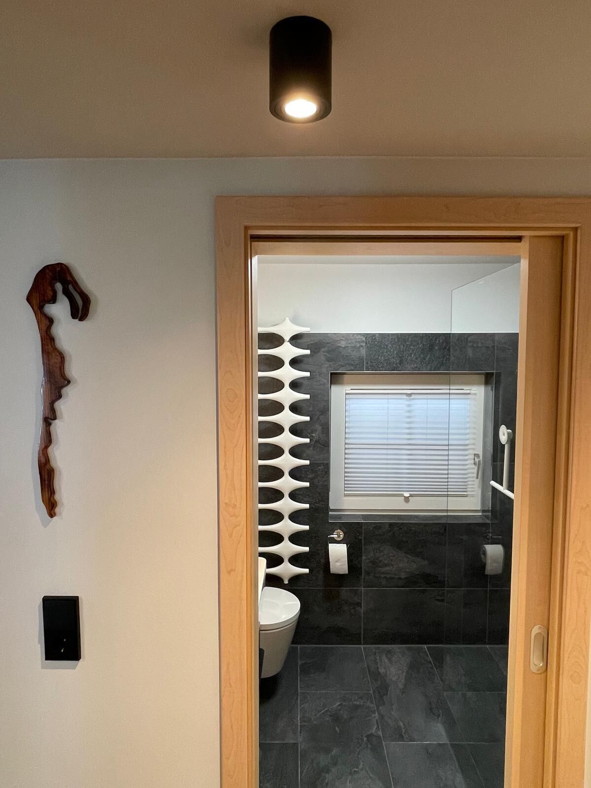 Une salle de bain moderne équipée de toilettes, d’un miroir et d’un espace douche.