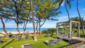 Une terrasse au bord de la plage, dotée de chaises longues, d’une pergola en bois et offrant une vue sur l’océan.