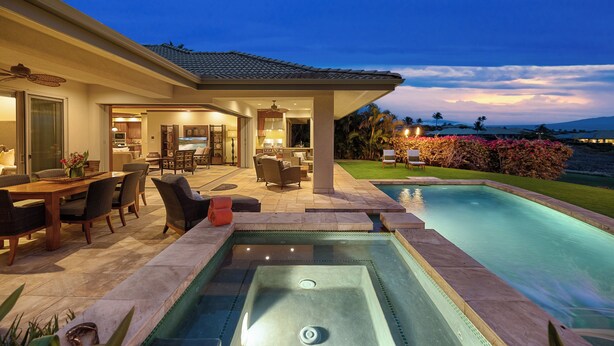 Une maison moderne dotée d’une piscine, d’un espace salon extérieur et d’un patio bien éclairé.