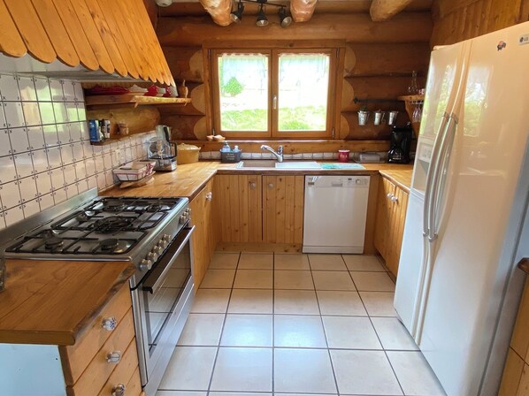 A kitchen with wooden cabinets, a gas stove, a dishwasher, and a refrigerator.