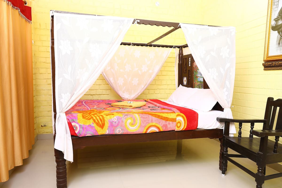 A bed with a canopy, a chair, and a yellow brick wall.
