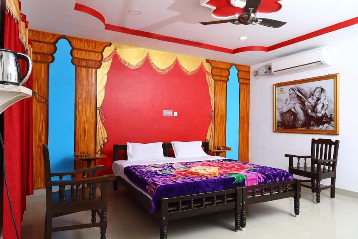 A bedroom with a bed, two chairs, a ceiling fan, and a wall-mounted air conditioner.