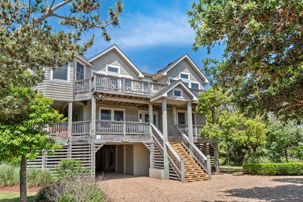 A two-story house with a covered porch, a staircase leading to the upper level, and a driveway.