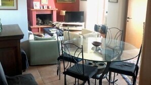 A living room with a glass dining table, black chairs, a sofa, and a TV. - Villetta Indipendente Panoramica e Immersa nel Verde (Fiuggi)
