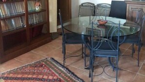 A dining area with a glass table and chairs, a bookshelf, and a patterned rug. - Villetta Indipendente Panoramica e Immersa nel Verde (Fiuggi)