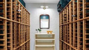 A wine cellar with wooden racks and a central shelf with a mirror and two golden bowls. - Big Beds for Everyone!  Braves Stadium only 2.5 miles away! (Marietta)