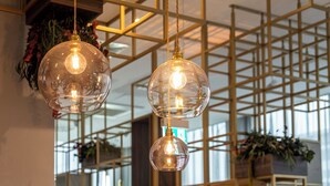 Three spherical pendant lights with exposed bulbs hanging from a ceiling with a geometric metal framework.