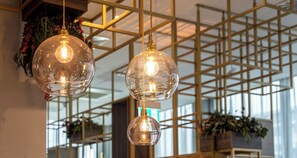 Three spherical pendant lights with exposed bulbs hanging from a ceiling with a geometric metal framework.