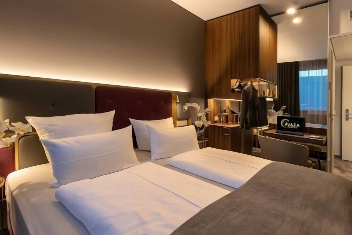 A hotel room with a large bed, a desk, a wardrobe, and a mirror.