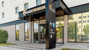 A modern building with a sign for 'Plaza Premium Hotel Reception' and a parking sign.