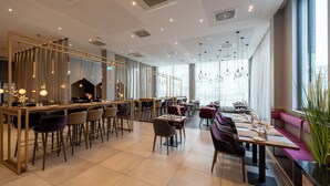 A modern restaurant with high ceilings, pendant lighting, and a mix of bar and dining areas. - PLAZA Premium München (Munich)