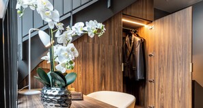 A modern bathroom with a wooden vanity, a white orchid vase, and a hanging coat rack.