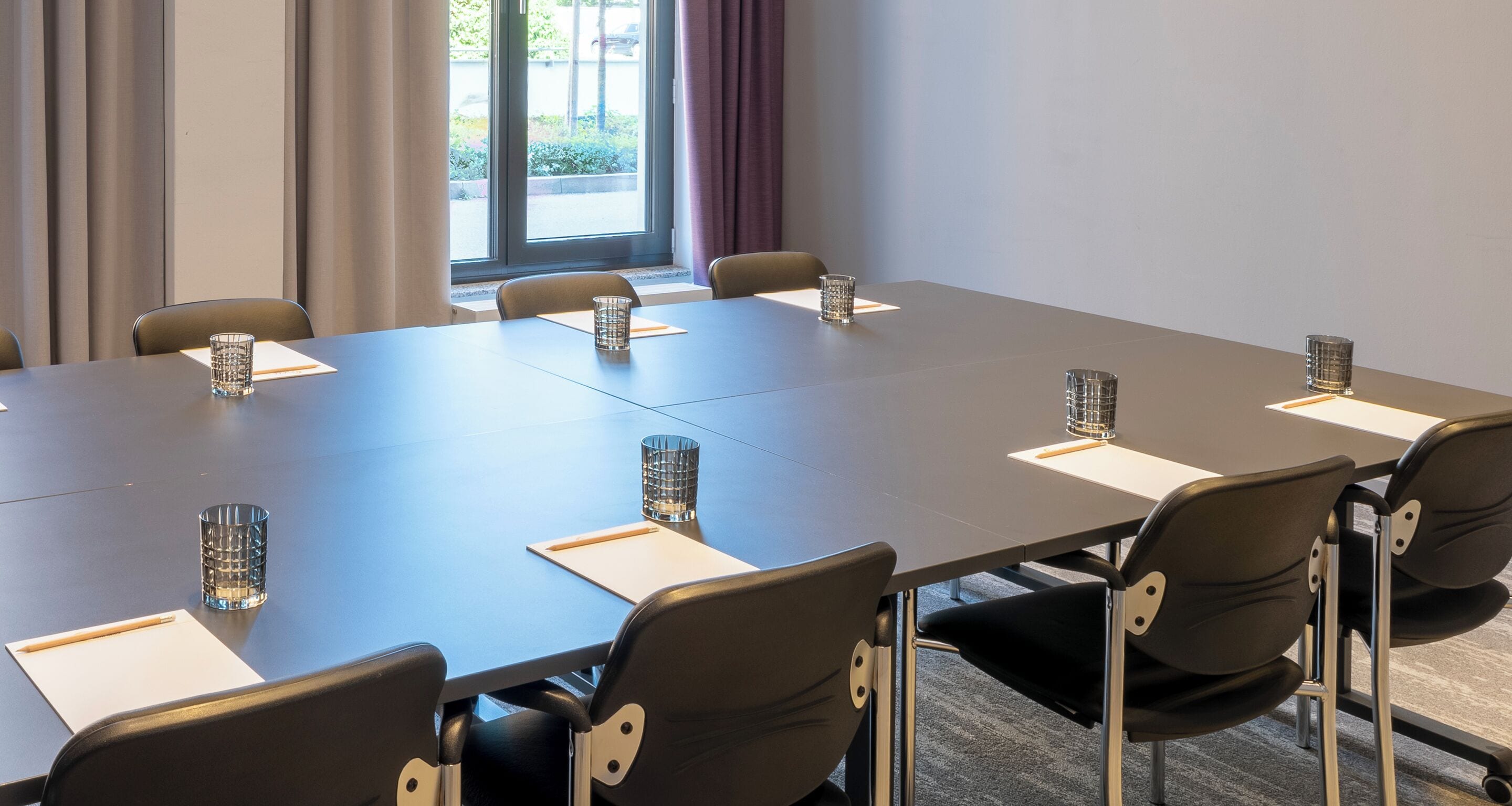 A conference room with a long table, six chairs, and glass candle holders.