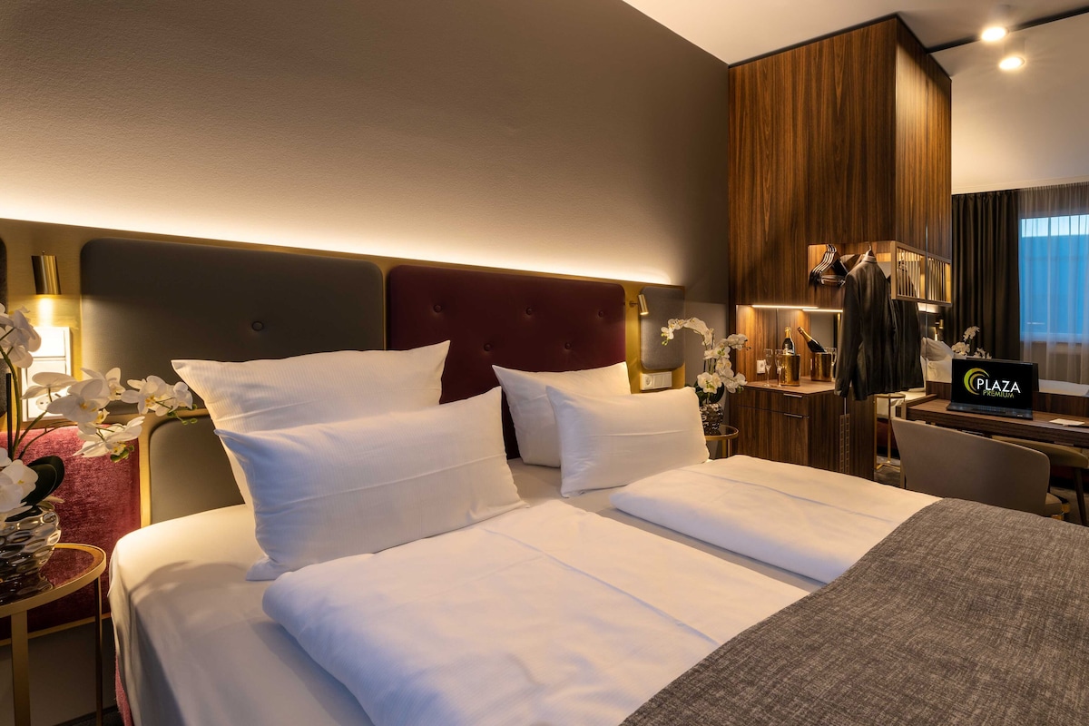 Habitación de hotel con cama, escritorio, minibar y puerta al baño.