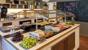 A buffet with various food items, including fruits, meats, and condiments.