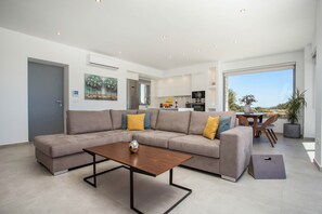 A modern living room with a sectional sofa, a coffee table, and a dining area with a table and chairs.