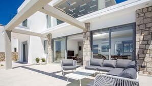 Eine moderne Außenpatio mit einer Sofagarnitur, einem Couchtisch und einem Korbstuhl.