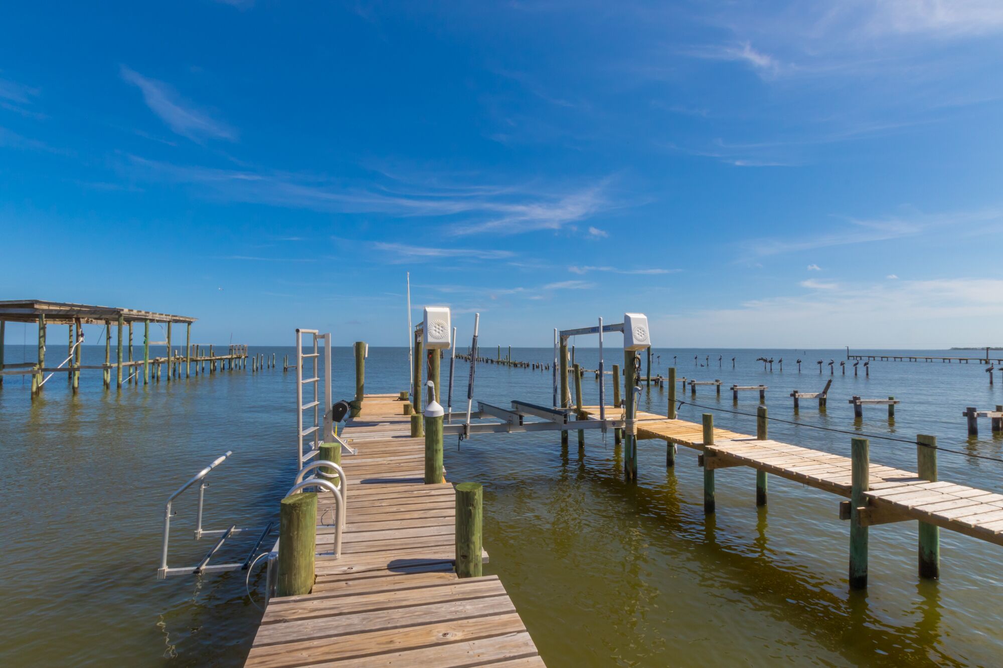 A wooden pier extending into calm waters, with a clear sky above.