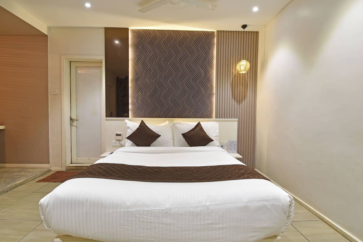 Una habitación de hotel moderna con una cama grande, una lámpara de pared y un diseño de pared estampado.