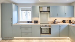Une cuisine moderne avec des meubles de couleur bleu clair, un four encastré et une fenêtre qui laisse entrer la lumière naturelle.