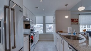 Une cuisine moderne dotée d’appareils électroménagers en acier inoxydable, d’une grande fenêtre et offrant une vue sur la ville.
