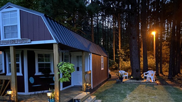 Eine rustikale Holzhütte mit Veranda, umgeben von einem Wald.