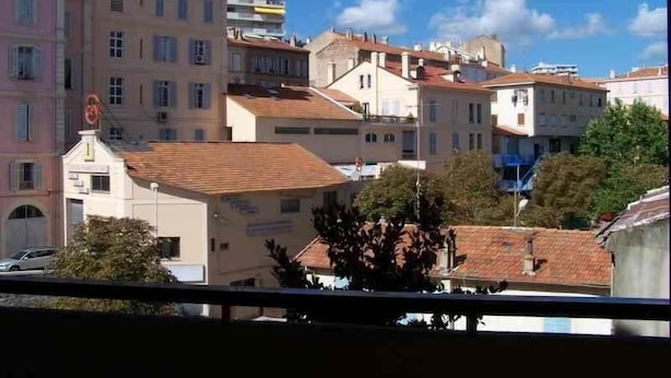 A view of a residential area with multi-story buildings, a visible street sign, and a clear blue sky.
