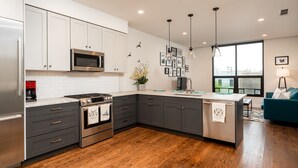 Una cocina moderna con armarios blancos, una estufa de acero inoxidable y una isla grande.