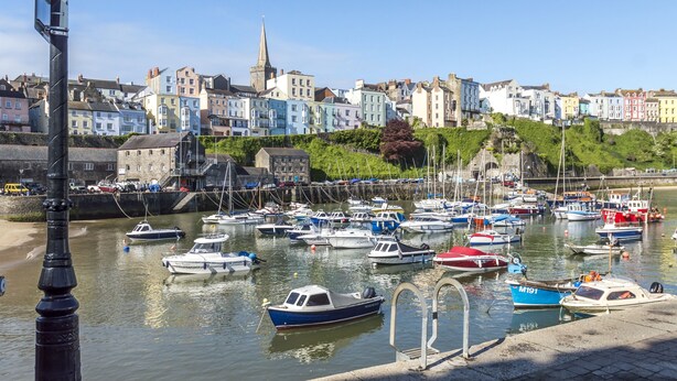 A harbor with numerous boats docked, a prominent church spire, and colorful buildings along the waterfront. - Tipyn O Haul - 1 Bed Apartment - Tenby (Tenby)