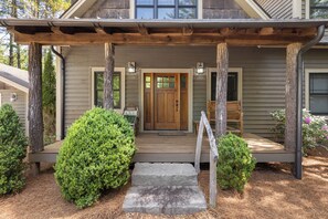 Une maison avec un porche en bois, une porte d’entrée et deux petites fenêtres.