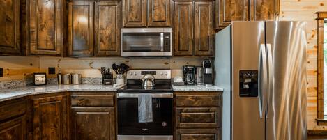 A kitchen with wooden cabinets, stainless steel appliances, and granite countertops.