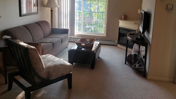 Una sala de estar con sofá, sillón, mesa de centro, televisión y chimenea.