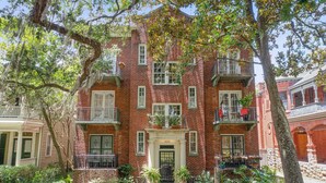 A red brick building with a central entrance, multiple windows, and balconies. - Oasis Overlooking Forsyth Park w/ Private Balcony & Parking by Lucky Savannah (Savannah)