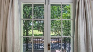 A white door with multiple glass panes, leading to an outdoor area with trees and a paved path. - Oasis Overlooking Forsyth Park w/ Private Balcony & Parking by Lucky Savannah (Savannah)
