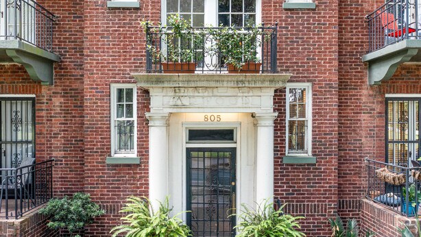 A brick building with a black door, number 805, and a small balcony with potted plants. - Oasis Overlooking Forsyth Park w/ Private Balcony & Parking by Lucky Savannah (Savannah)