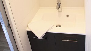 A modern bathroom with a white sink, black cabinets, and a mirror above the sink. - 20m from ski slopes, 2nd floor, balcony, tv, ski locker, 25m², Serre Chevalier (Briançon)