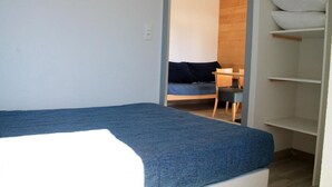 Quarto com uma cama de solteiro, uma escrivaninha e uma cadeira.