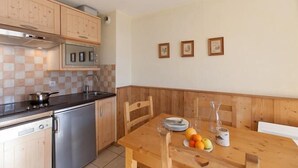 Une cuisine dotée de meubles en bois, d’un lave-vaisselle en acier inoxydable et d’une table à manger mise avec des assiettes, des verres et des fruits.