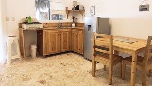 A compact kitchen with wooden cabinets, a gas stove, a sink, and a refrigerator.