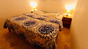 A bedroom with a large bed, two bedside lamps, a window with curtains, and a carpeted floor.